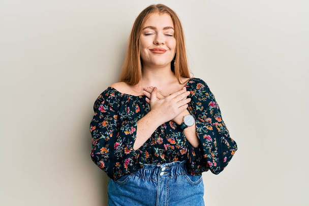 Young beautiful redhead woman wearing casual floral clothes smiling with hands on chest, eyes closed with grateful gesture on face. health concept.  - Photo, Image