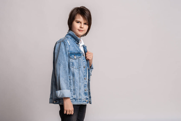 スタジオでポーズをとっているジーンズジャケットに身を包んだ11 〜 13歳のイケメンファッション少年。モデルテスト。ファッションと人々のコンセプト - 写真・画像