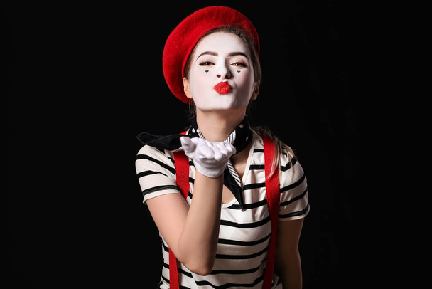 Feminino pantomimista soprando beijo no fundo escuro - Foto, Imagem