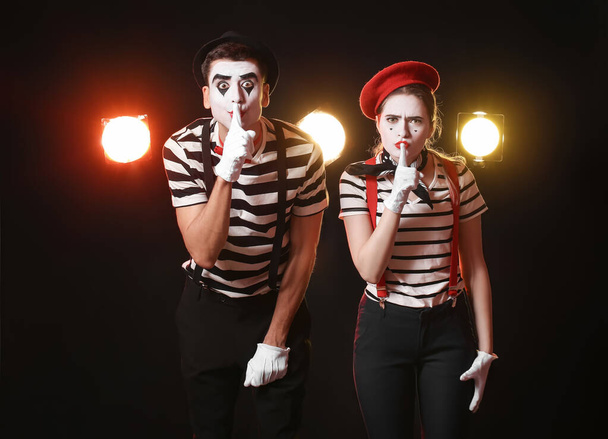 Férfi és női pantomimisták csendgesztust mutatnak sötét háttérrel - Fotó, kép