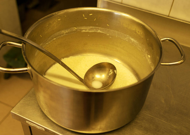 olla de metal con taza en la tapa de la estufa con sopa de leche, cocina de la escuela, comer concepto de cocina, olla de cocina de metal - Foto, imagen