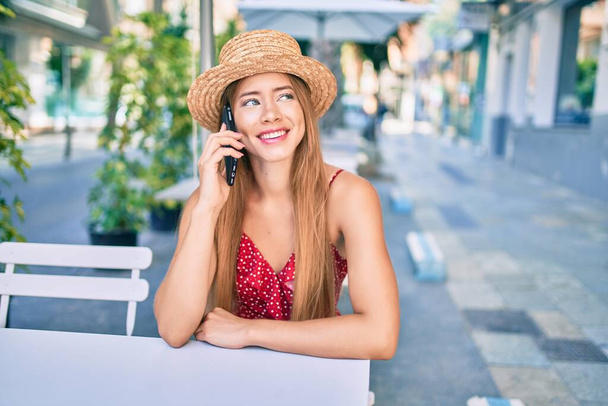 Young caucasian tourist girl smiling happy talking smartphone sitting at the coffee shop terrace. - Photo, Image