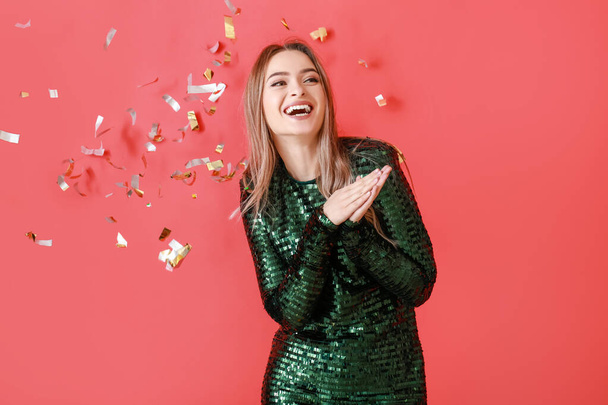 Happy young woman and falling confetti on color background - Foto, immagini