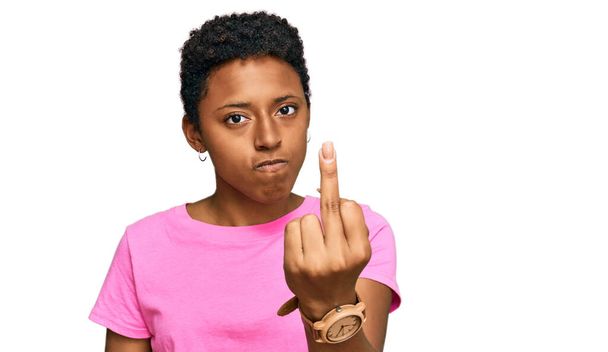 молодая африканская американка в повседневной одежде, показывающая средний палец, невежливая и грубая...  - Фото, изображение
