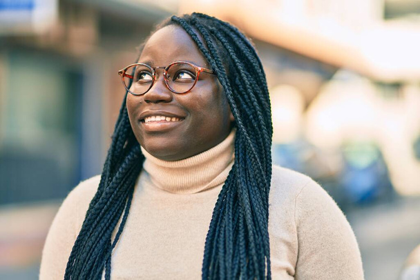 jonge afrikaanse amerikaanse vrouw glimlachen gelukkig staan in de stad. - Foto, afbeelding