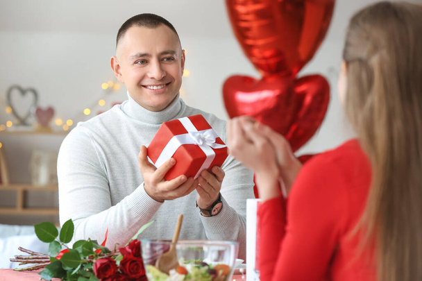 Jeune homme saluant sa petite amie le jour de la Saint Valentin à la maison - Photo, image