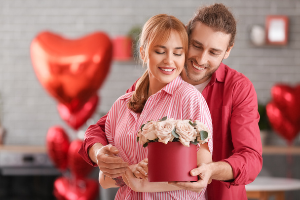 Junger Mann grüßt seine Freundin am Valentinstag zu Hause - Foto, Bild