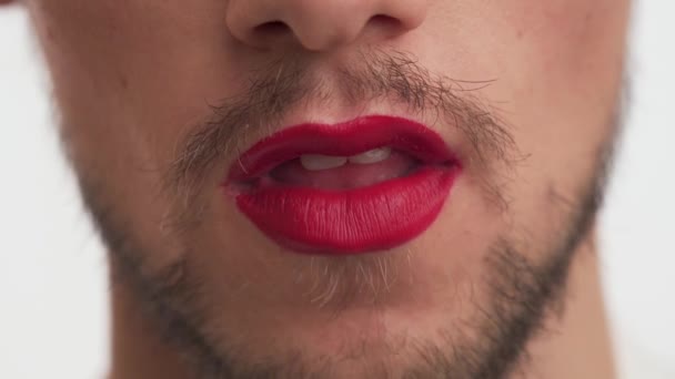 Junge schöne kaukasische metrosexuelle oder homosexuelle Mann mit dunkelschwarzem Bart, Schnurrbart tragen roten Lippenstift auf den Lippen, offenen Mund weit, spielen mit der Zunge auf weißem Hintergrund Nahaufnahme. Porträt eines lustigen Kerls Narr. - Filmmaterial, Video