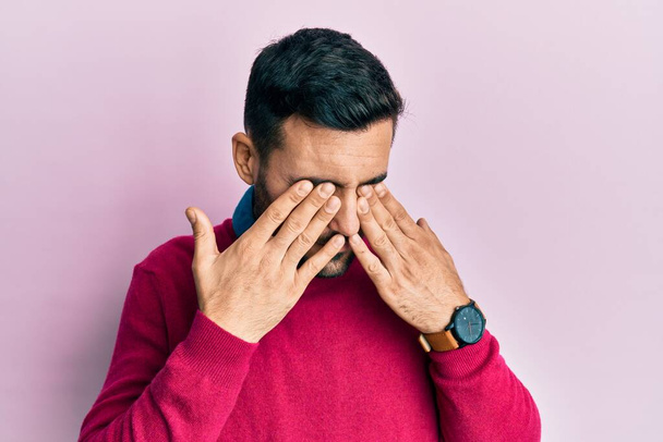 Junger hispanischer Mann in lässiger Kleidung reibt sich die Augen vor Müdigkeit und Kopfschmerzen, schläfriger und müder Miene. Sehschwäche  - Foto, Bild