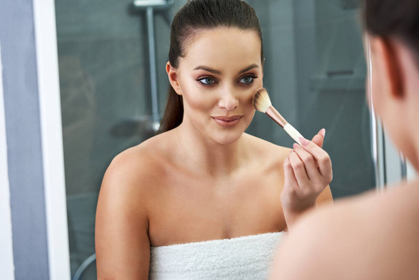 Nainen soveltamalla meikkiä kylpyhuoneessa suihkun jälkeen - Valokuva, kuva