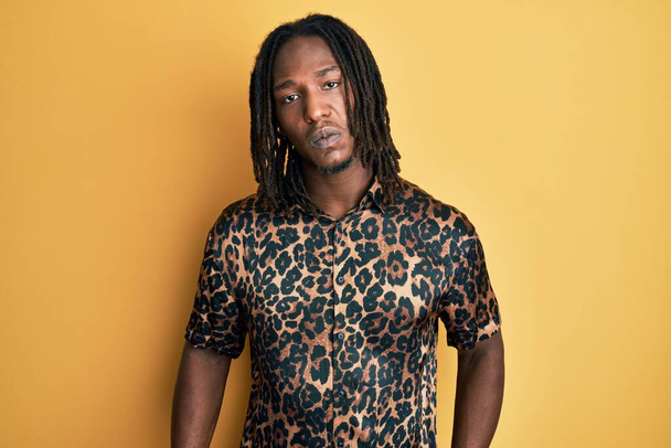 Afroamerikanischer Mann mit Zöpfen im Leoparden-Animal-Print-Hemd deprimiert und besorgt vor Not, weint wütend und ängstlich. Traurige Miene.  - Foto, Bild