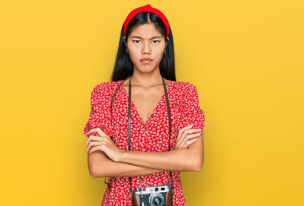 Beautiful young asian woman wearing dress and vintage camera skeptic and nervous, disapproving expression on face with crossed arms. negative person.  - Foto, Bild