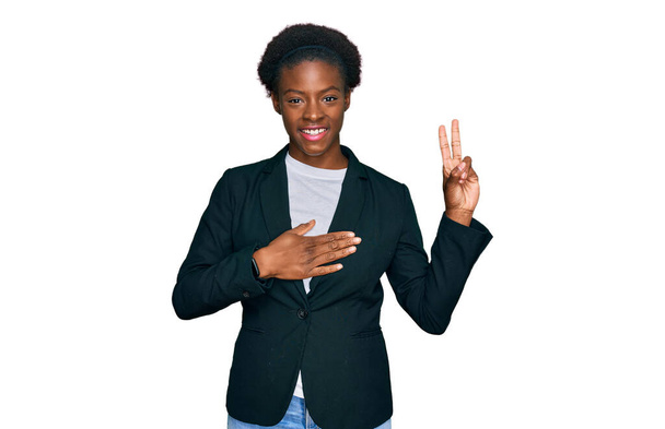 Jong Afrikaans-Amerikaans meisje in zakelijke kleren, lachend met de hand op de borst en vingers omhoog, een trouw eed afleggend  - Foto, afbeelding