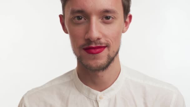 Young metrosexual or gay man sincerely laughs, smiles isolated on white background. Male with black beard wear shirt, make-up  red lipstick on lips. Close-up portrait of one fashion model happy guy. - Footage, Video