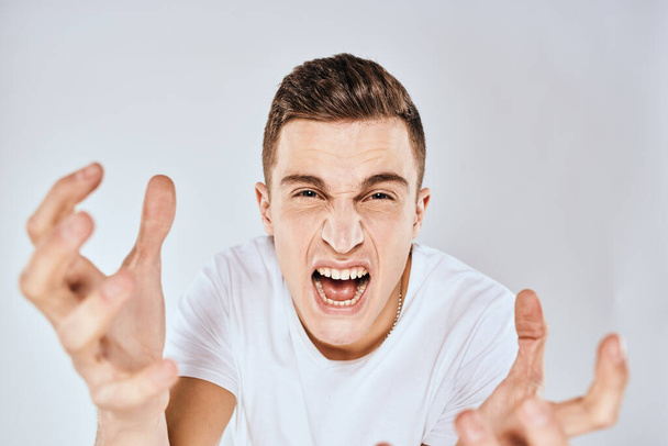 Mann im weißen T-Shirt missbilligt Mimik gestikulierend mit den Händen - Foto, Bild