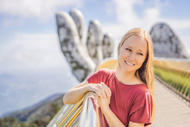 Young woman tourist at Famous tourist attraction - Golden bridge at the top of the Ba Na Hills, Vietnam - Photo, image
