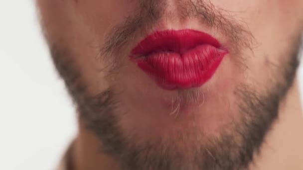 Ein netter Mann mit aufgemalten Lippen in rotem Lippenstift, dickem Bart, weit geöffnetem Schnurrbart, legt süße Diätbonbons, isst, kaut genüsslich isoliert auf weißem Hintergrund. Konzept der richtigen Ernährung - Filmmaterial, Video