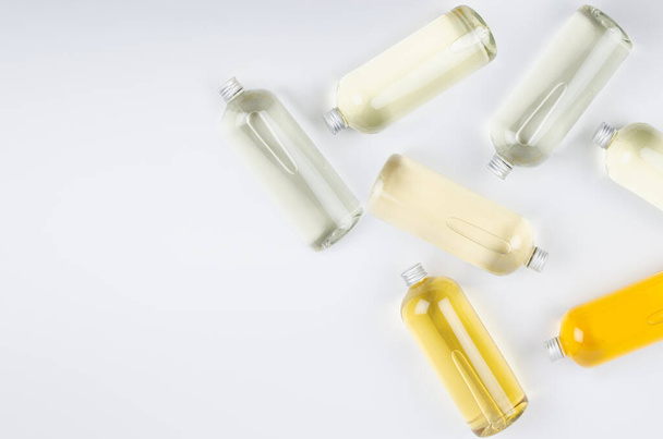 Abstract cosmetic border of lying bottles with different pale colors liquid, silver cap on white background, top view, copy space. - Fotó, kép