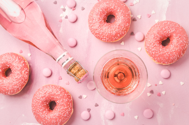 Růžové víno nebo koktejl s růžovými koblihami a růžové čokoládové fazole na růžovém pozadí - Fotografie, Obrázek