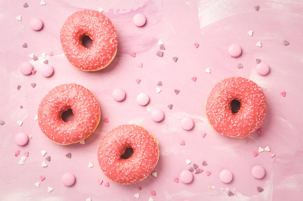 Donuts with pink icing and pink chocolate beans on pink background - Photo, Image