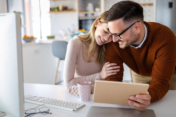 Beautiful couple working on a tablet at home. People, business, technology concept - Photo, Image