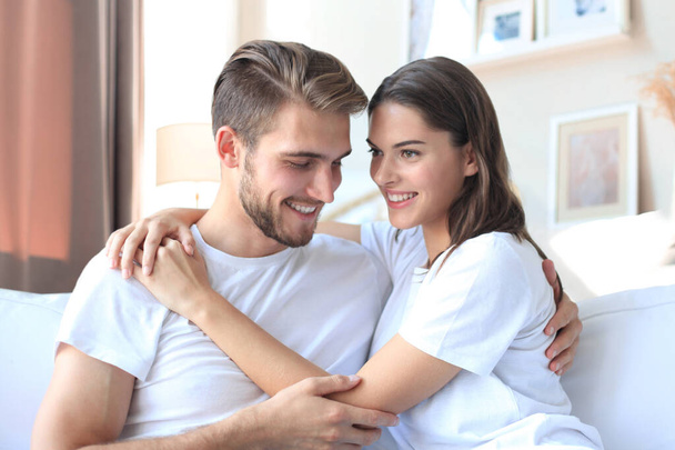 Happy young couple hugging and looking at each other at home interior - Foto, Imagem
