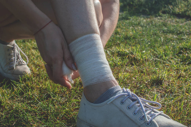 Самоперевязка. Молодая женщина перевязывает ноги, чтобы защитить сухожилия во время. Боль в растяжении лодыжки - Фото, изображение