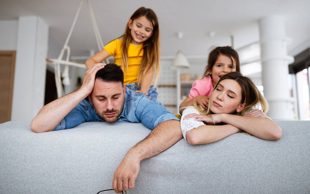 Tired mother and father feels annoyed exhausted while noisy children at home - Fotoğraf, Görsel