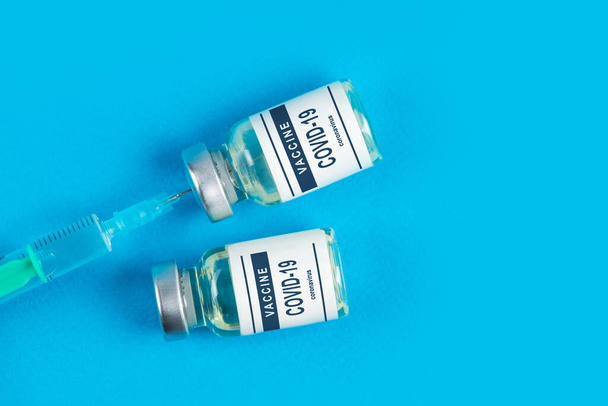 Vaccinatie. Spuit en vaccin COVID-19. Coronavirus op blauwe achtergrond. - Foto, afbeelding