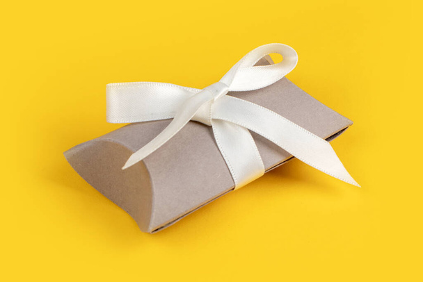 Caja de regalo gris con cinta plateada sobre fondo amarillo. - Foto, imagen