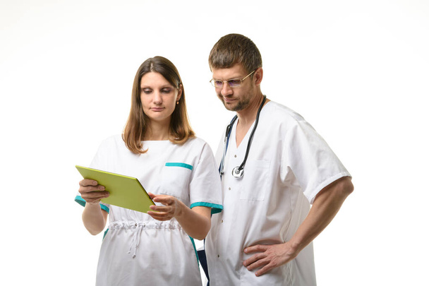 Medico e infermiere discutono i test del paziente, guardando attentamente nello schermo di un tablet - Foto, immagini