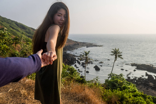Tiro de uma jovem mulher liderando alguém pela mão na praia - Foto, Imagem