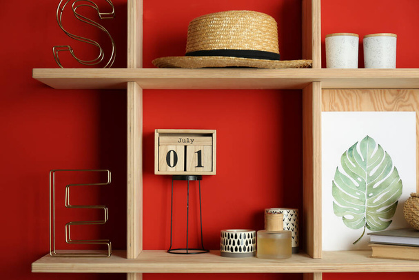Stylish wooden shelves with decorative elements on red wall - Valokuva, kuva