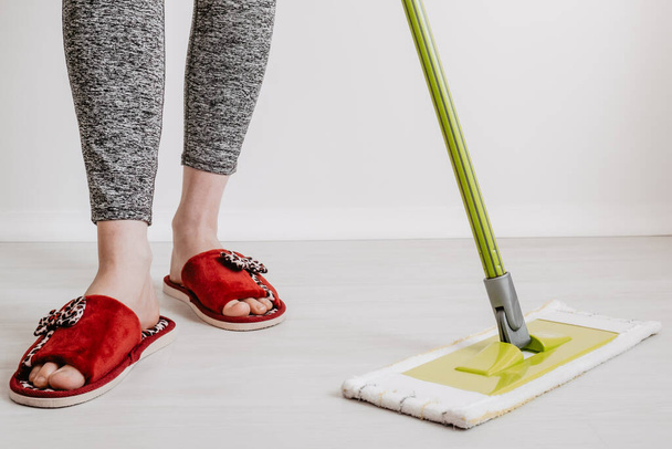 House cleaning concept. Close-up of a mop and female feet in house slippers. Space for text. - Fotó, kép