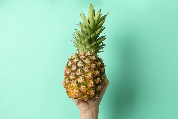 Samičí ruka držet zralé ananas na mátovém pozadí - Fotografie, Obrázek