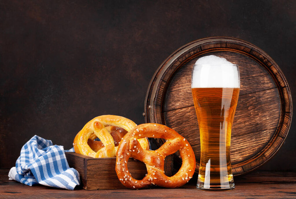 Lager bier met zelfgemaakte pretzels en oud houten biervat. met kopieerruimte - Foto, afbeelding