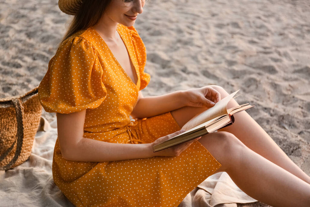 Young woman reading book on sandy beach - Zdjęcie, obraz
