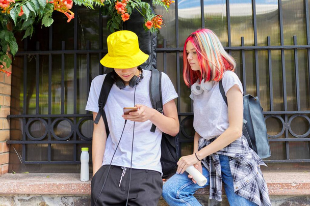 Teenagers students guy and girl look in smartphone screen - Фото, изображение