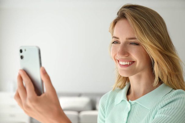 Young woman unlocking smartphone with facial scanner indoors. Biometric verification - Φωτογραφία, εικόνα