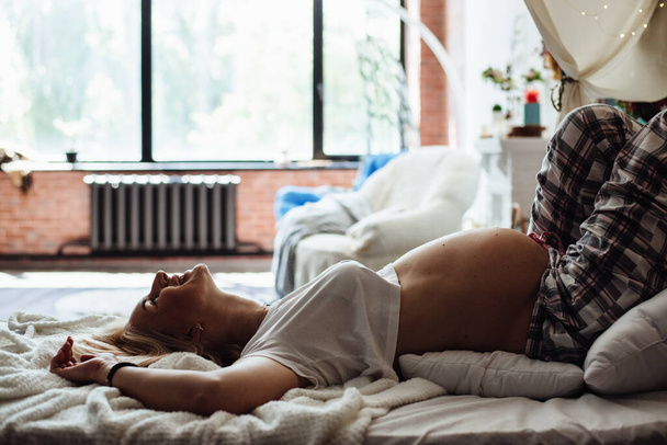 Schwangerschaft, Ruhe, Menschen und Erwartungskonzept - Nahaufnahme einer glücklich lächelnden Schwangeren, die zu Hause im Bett liegt - Foto, Bild