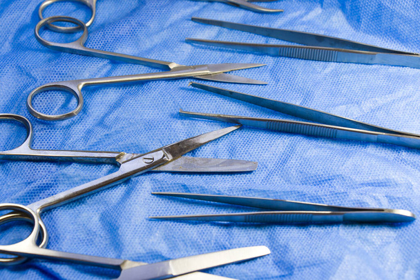 An isolated closeup of stainless steel dissection kit on blue medical cloth - Foto, imagen