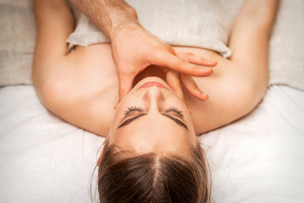 Masaje de barbilla o cuello de una joven por la mano de un masajista masculino en un salón de spa - Foto, Imagen