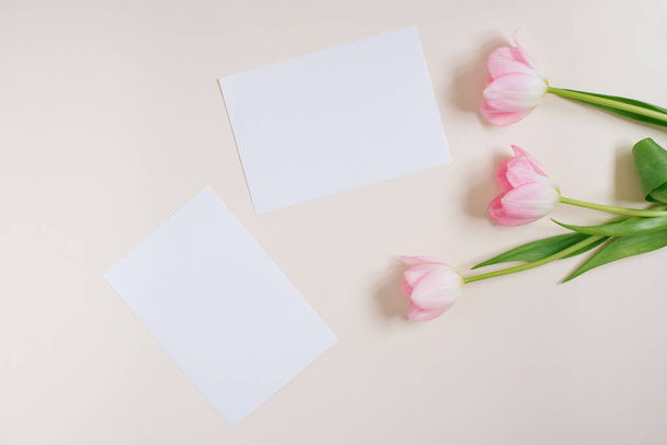 Hermosas flores de primavera composición. Marco en blanco para texto, flores de tulipanes rosados sobre fondo beige. San Valentín, Pascua, Cumpleaños, Feliz Día de la Mujer. Plano, vista superior, espacio para copiar - Foto, imagen