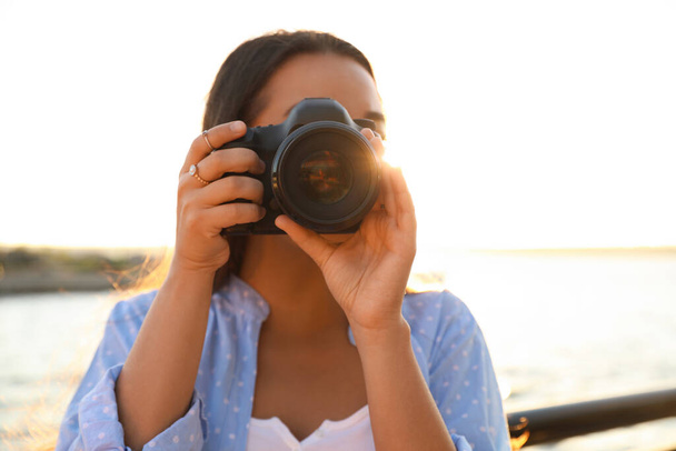 Jonge fotograaf fotograferen met professionele camera buiten - Foto, afbeelding