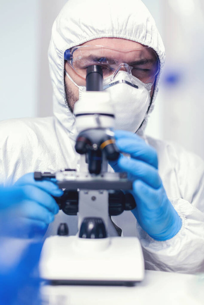 Technik laboratoryjny w ppe analizujący próbkę na mikroskopie - Zdjęcie, obraz