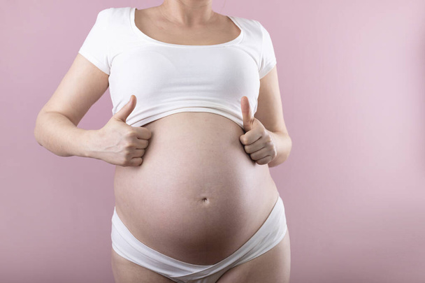 A pregnant woman shows a thumb up. Big pregnant belly. - Valokuva, kuva