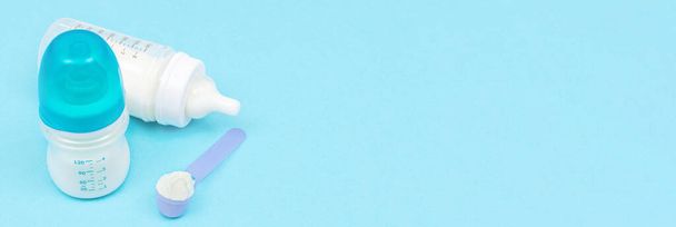 Banner με γάλα σε σκόνη για το μωρό σε κουτάλι μέτρησης κοντά μπουκάλια μωρό σε μπλε φόντο. Έννοια διατροφής βρεφών - Φωτογραφία, εικόνα