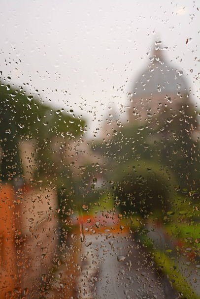 Blurred Dome of St Peters Basilica in Vatican City through raindrops on glass with trees on front view, Rome, Italy. Roman Catholic Church - 写真・画像