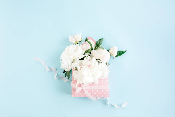 White bouquet of peonies in an envelope for flowers on blue background. Minimal floral concept greeting card. Flat lay, top view.  - Photo, Image