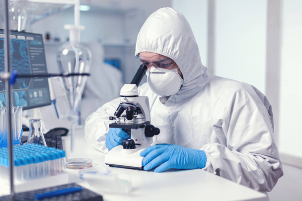 Científico masculino trabajando con microscopio investigando cura - Foto, Imagen